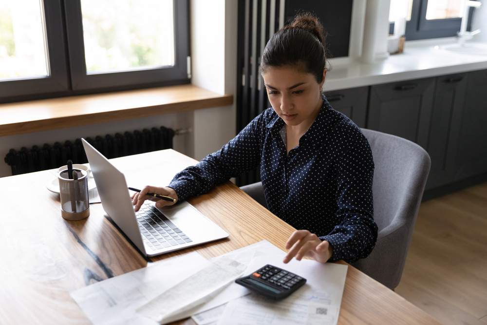 Woman With Dark Hair Working on a Desk with Calculator